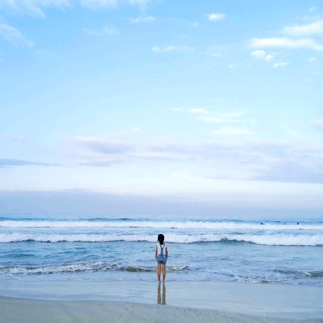 夕方のビーチに立つわが娘