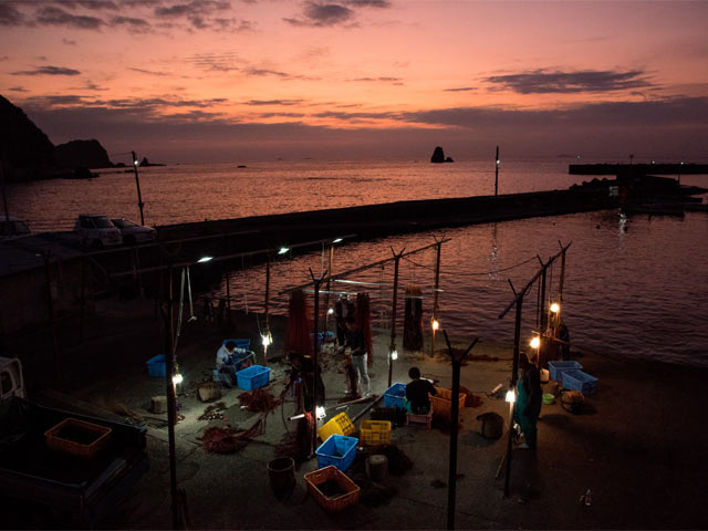 朝焼けの中で準備中の漁師さん