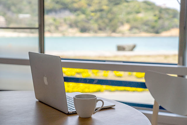海が見えるテーブルの上にノートパソコン