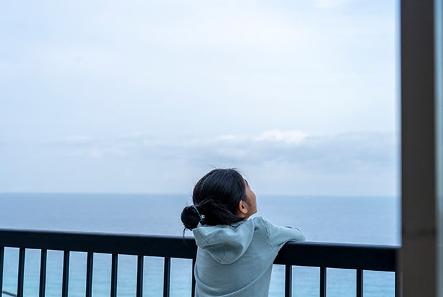ベランダで海を眺める娘