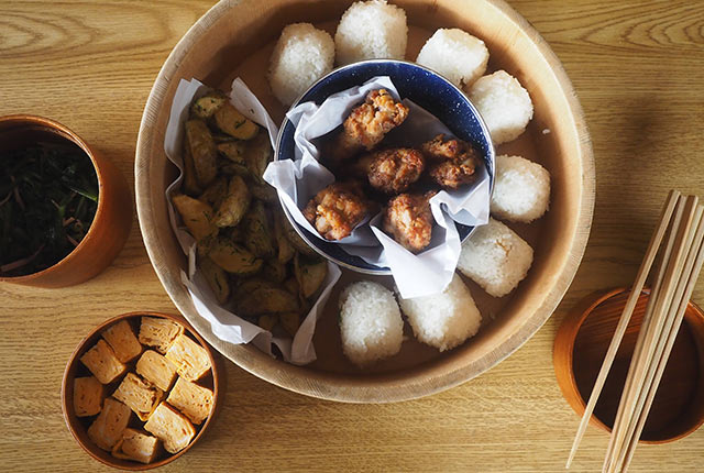 木桶に入ったおにぎりと鳥の唐揚げ、フライドポテト