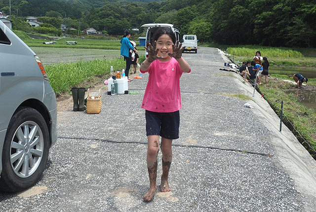 泥だらけの手を見せてカメラに構える娘の友達