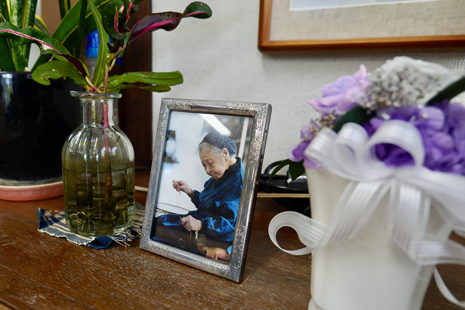 栽培から織りまでの地道な工程を体系化し、村人が一丸となって作業を続けている。この形を現在へ繋いだ平良敏子さん。芭蕉布会館にはそっと写真が飾ってあった。