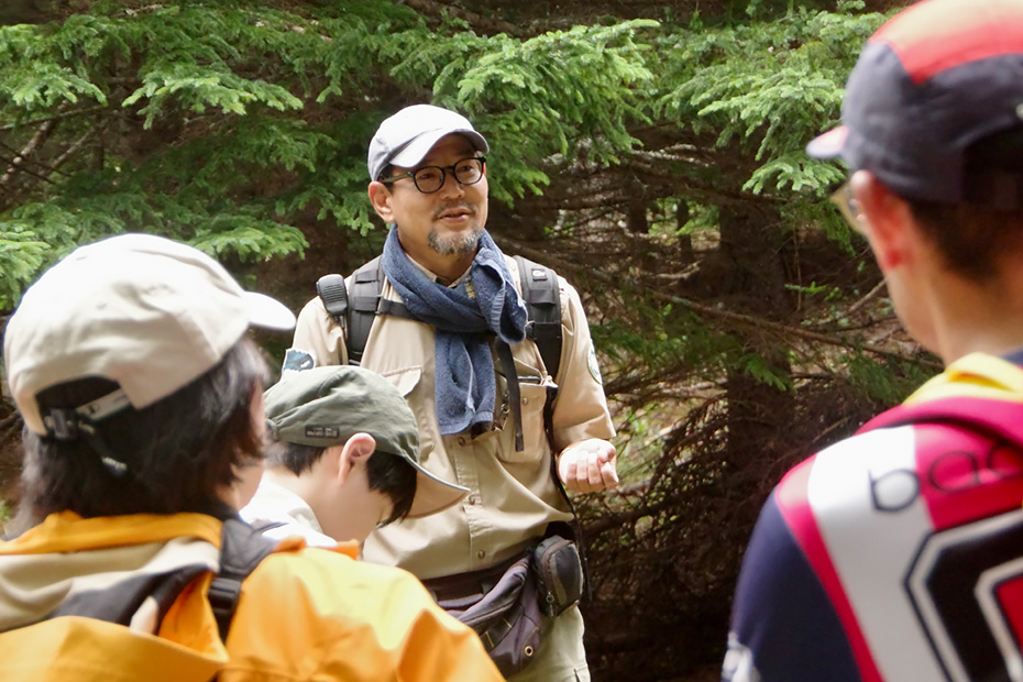 開拓地を森に再生する現場を案内してくれるツアーに参加した。解説をする中西将尚さん。