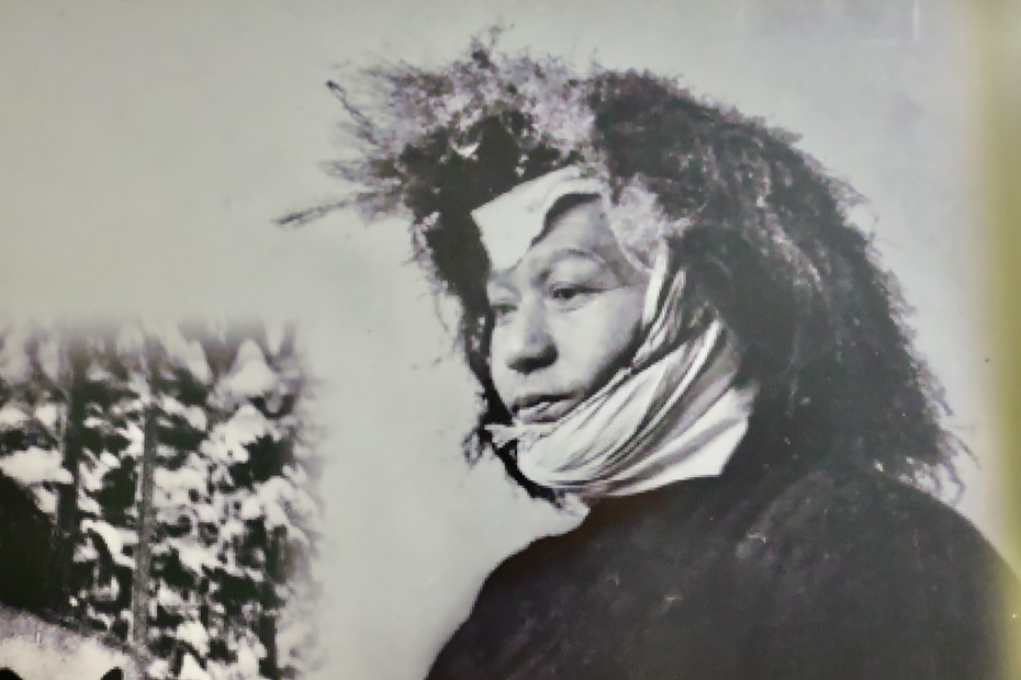 アミビタ（トシミで作った編み笠）を被るマタギ。冬は暖かく夏は涼しい。西目屋中央公民館「風土回廊」より