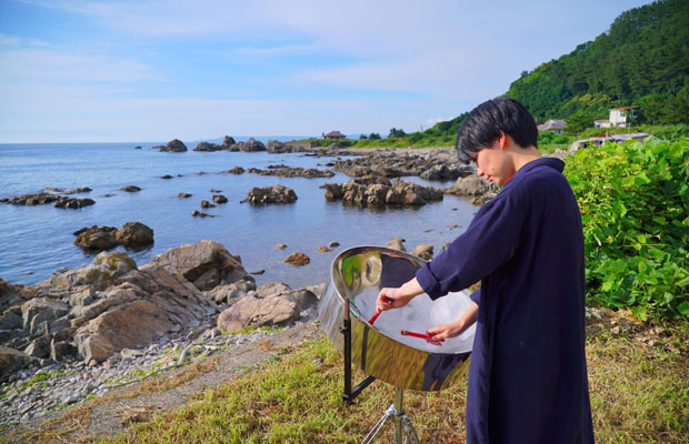 休日に趣味である「スティールパン」(ドラム缶からつくられた打楽器)を、大自然をバックに演奏する永井さん。(写真提供:永井温子)